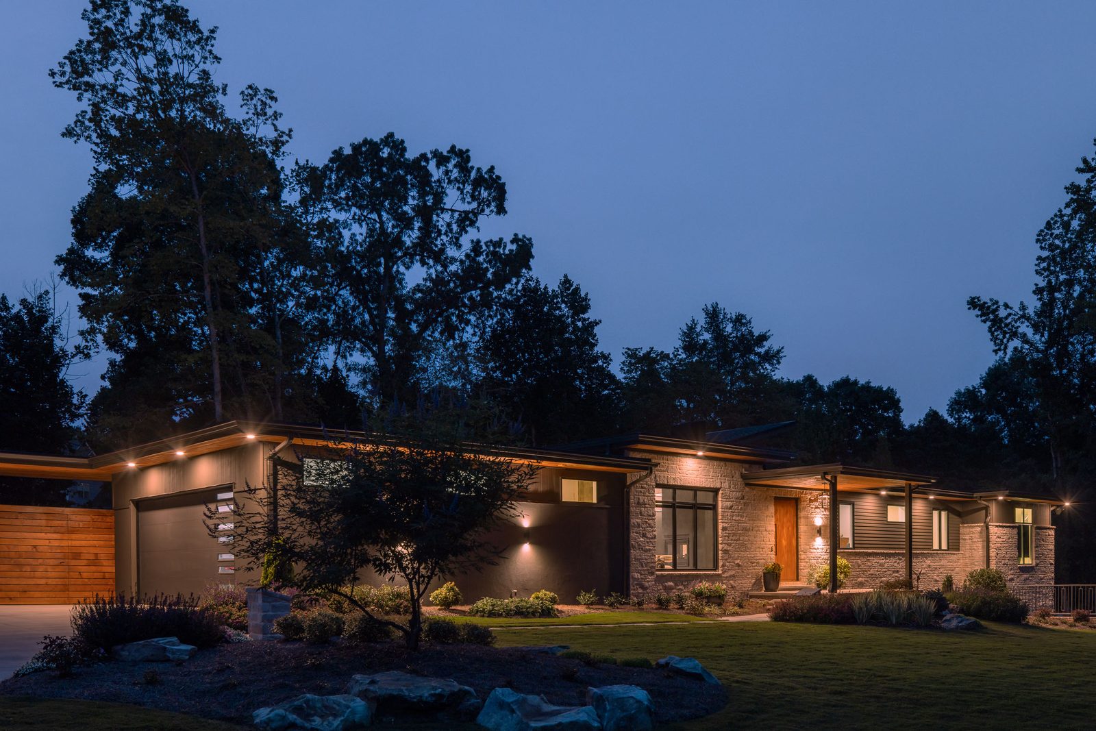 Exterior after dark with the landscape lighting on — The Ortiz Home, custom home built by Ironwood Construction Group in Sugar Hill, Georgia
