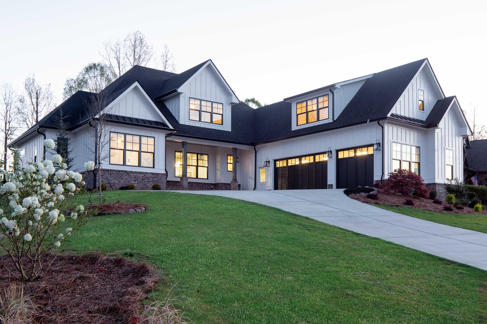 Front elevation of the white board-and-batten farmhouse with three-car garage — Glausier, custom home built by Ironwood Construction Group