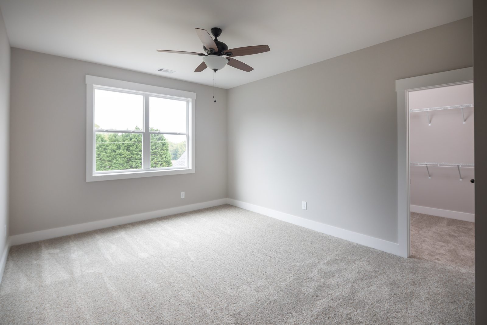 Secondary bedroom with carpet and walk-in closet — Shadburn Ferry, custom home built by Ironwood Construction Group in Buford, Georgia